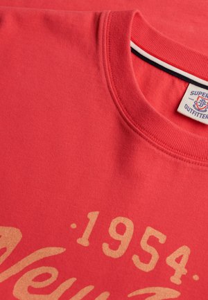 Rød crew-neck T-shirt med beige "1954" og delvist kursiv tekst, der har et Superdry Outfitter-mærke inde i kraven.