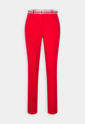 Red slim-fit trousers with front pockets and a white belt featuring black and red stripes and a silver buckle.