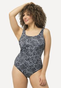 Maillot de bain une pièce noir et blanc présentant un motif en forme de vagues, un décolleté défini, de larges bretelles et une texture de tissu lisse et extensible.