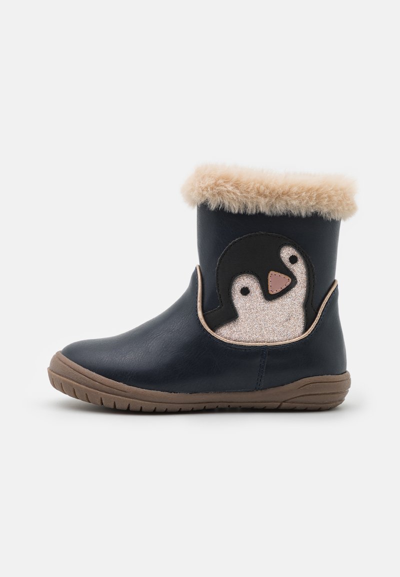 Bottes en simili cuir bleu marine avec un revers en fourrure, ornées d'un accent de pingouin noir et pailleté sur le côté, avec une semelle en caoutchouc marron.