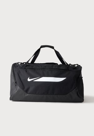 Sac de sport noir Nike avec doubles poignées, poche latérale en mesh et grand logo blanc Swoosh à l'avant sur un fond uni.