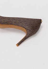 Escarpin à talon haut marron à motifs, avec un bout pointu et une semelle lisse couleur tan. Présente un accent métallique à l'arrière et une surface texturée.