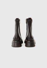 Brown leather ankle boots with a chunky sole, side zippers, and pull tabs at the back. Smooth texture and sleek, fitted design.