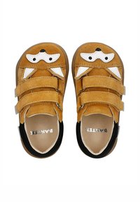 Scarpe in suede marrone con tre cinturini in velcro, dotate di dettagli in pelle bianca che ricordano il muso di un cane e una suola in gomma nera.