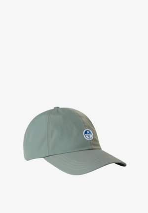 Cappellino da baseball verde chiaro con visiera cucita, dettagli nelle pannellature laterali e una toppa circolare con un logo che presenta dettagli blu e bianchi.