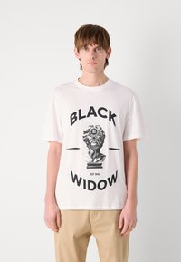 Hvit bomull T-skjorte med grafisk design av en brystbyste, med fet svart tekst som leser "BLACK WIDOW" og "EST 1993" under.