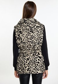 Puffer vesta s leopardím potiskem, stojáčkovým límcem, elastickým pasem a dlouhými černými rukávy. Texturovaná látka, béžovo-černá barevná kombinace.