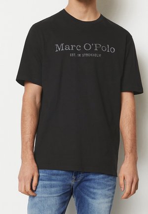 Zwart katoenen T-shirt met korte mouwen, met de tekst "Marc O'Polo EST. IN STOCKHOLM" in grijs over de borst. Eenvoudig ontwerp.