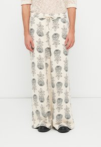 Pantalones de pierna ancha de color claro con un estampado floral y de hojas en gris. Fabricados con un material suave, cuentan con una cintura elástica y cordón.