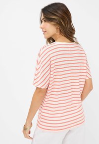 Kvindernes stribede t-shirt i lys pink og hvid, korte ærmer, afslappet pasform, blød tekstur, sidelæg og en rund kant.