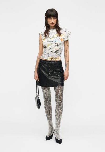 Λευκό τοπ με κοντά μανίκια και πολύχρωμα αφηρημένα σχέδια, συνδυασμένο με μαύρη μίνι φούστα από δέρμα, καλσόν με σχέδιο φίδι και μαύρες γόβες.