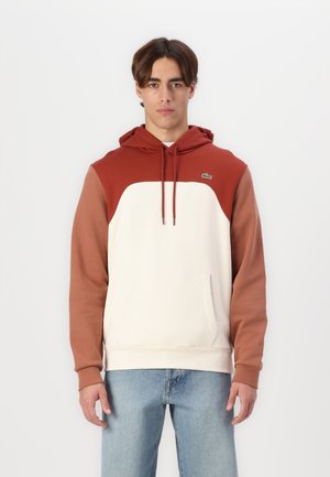 Sudadera con capucha que presenta un cuerpo crema con mangas en tonos óxido y marrón, hecha de una mezcla de algodón. Incluye un bolsillo frontal y detalle de logotipo.