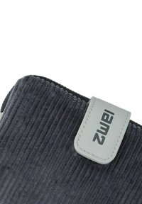 Zwart ribbelstof met een witte gestikte rechthoekige label met de tekst "Iamz" bevestigd nabij de bovenrand.