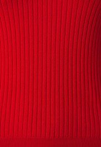 Roter gerippter Strickstoff mit vertikalen Streifen, der eine glatte Textur und ein elastisches Passformdesign aufweist, ideal zum Schichten oder als Einzelstück.