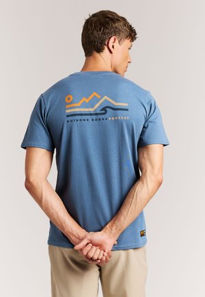 Blauw katoenen T-shirt met een afbeelding van een berg en een golf in oranje en zwart op de achterkant. Korte mouwen, losse pasvorm.