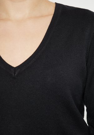 Zwarte, lichte trui met een diepe V-hals en geribbelde textuur. Het materiaal lijkt zacht en heeft een aangesloten silhouet.