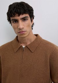 Brun tekstureret zip-up sweater med krave, der har en tætsiddende pasform og synlige sømdetaljer.