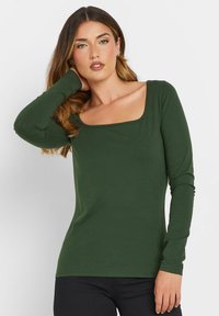 Langarmshirt in dunkelgrün mit quadratischem Ausschnitt, glatter Textur und figurbetontem Design. Minimalistischer Stil ohne sichtbare Muster.