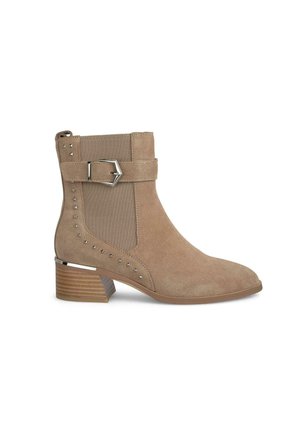 Beige Wildleder-Ankelboots mit strukturierter Oberfläche, ausgestattet mit einer seitlichen Schnalle, Nietenakzenten und einem gestapelten Absatz für zusätzlichen Stil.