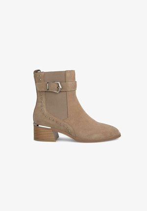 Bottines en suède beige avec une finition texturée, dotées d'une boucle latérale, d'accents de clous et d'un talon empilé pour un style supplémentaire.