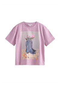 Lilac cotton t-shirt featuring a graphic of black cowboy boots with white embroidery, surrounded by flowers and oranges on a tiled background.