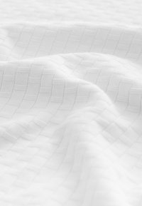 White textured fabric featuring a woven pattern of squares, creating a subtle depth. The material appears lightweight and smooth.