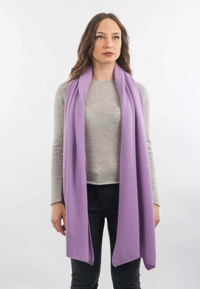 Lavendel lang tørklæde lavet af blødt stof, draperet løst omkring halsen. Kanterne er let flossede, hvilket giver et afslappet look.