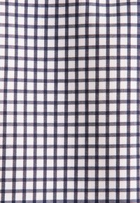 Tkanina bawełniana w granatowo-białą kratkę, z małymi kwadratami obramowanymi cienkimi czerwonymi nitkami, gładka w dotyku.