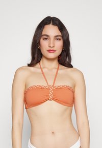 Top de bikini bandeau laranja com detalhes trançados no centro e nos ombros. Têxtil suave e alças ajustáveis.