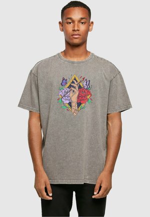 Grå oversized t-shirt i vasket bomuld med et centralt grafisk motiv af en hånd omgivet af røde og lilla blomster og sommerfugle.