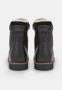 Botine negre din piele cu un finisaj texturat, guler căptușit cu lână și o talpă robustă din cauciuc, având detalii de cusătură vizibile.