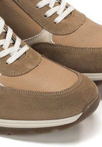 Sneaker beige in una combinazione di materiali suede e mesh, punta rotonda, lacci bianchi e suola in gomma testurizzata.