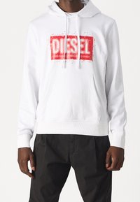 Vit hoodie i bomull med en framficka. Har en framträdande röd "DIESEL"-logotyp i tryckt, slitaget look. Elastiska ärmslut och fåll.