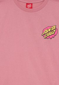Rosa bomull T-shirt med en svart och gul "Santa Cruz" logotyp på vänster bröstområde, med rund hals och korta ärmar.