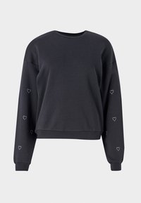 Sweat-shirt noir à manches longues avec petits motifs de cœurs blancs sur les deux manches, poignets et ourlet côtelés, sur un fond uni.