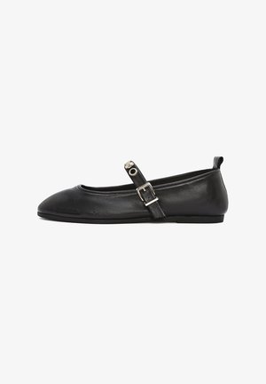 Ballerines en cuir noir avec un bout arrondi, une bride de cheville et un détail de boucle en argent. Texture lisse et design minimaliste.