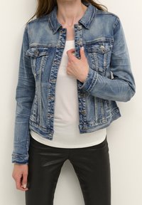 Denimjacka i ljusblått med knäppning fram, bröstfickor och croppad nederkant, med blekta och slitna detaljer.