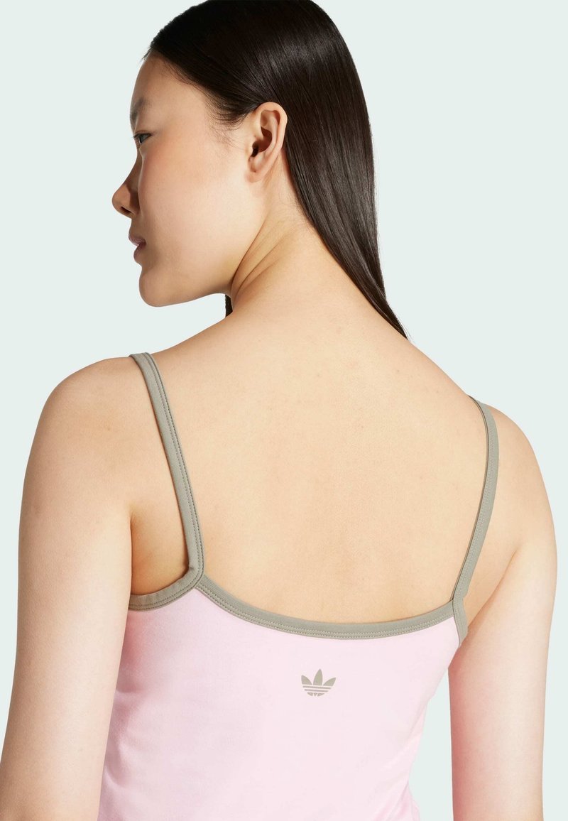 Helles pinkes Top mit grauen Trägern, das auf der Rückseite ein minimalistisches Logo zeigt. Glatte Textur, lässiges Design und figurbetonte Form.