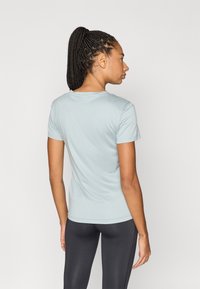 Ανοιχτό μπλε εφαρμοστό T-shirt από απαλό ύφασμα, με στρογγυλή λαιμόκοψη και κοντά μανίκια, σε συνδυασμό με μαύρο κολάν.