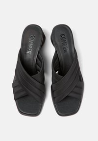 Sandales noires à glissière avec des brides croisées en matériau doux, présentant un bout carré plat et des semelles texturées, portant la marque "CAMPER."