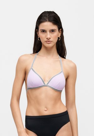 Kobieta ubrana w jasnofioletowy top bikini typu halter z czarną lamówką i czarne majtki bikini, skierowana przodem, na jednolitym tle.