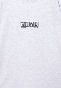 Light gray t-shirt featuring a graphic with "STWD" in black and colored boxes, text reading "STAY UNITED DEPT. 1991" below. Soft cotton fabric.