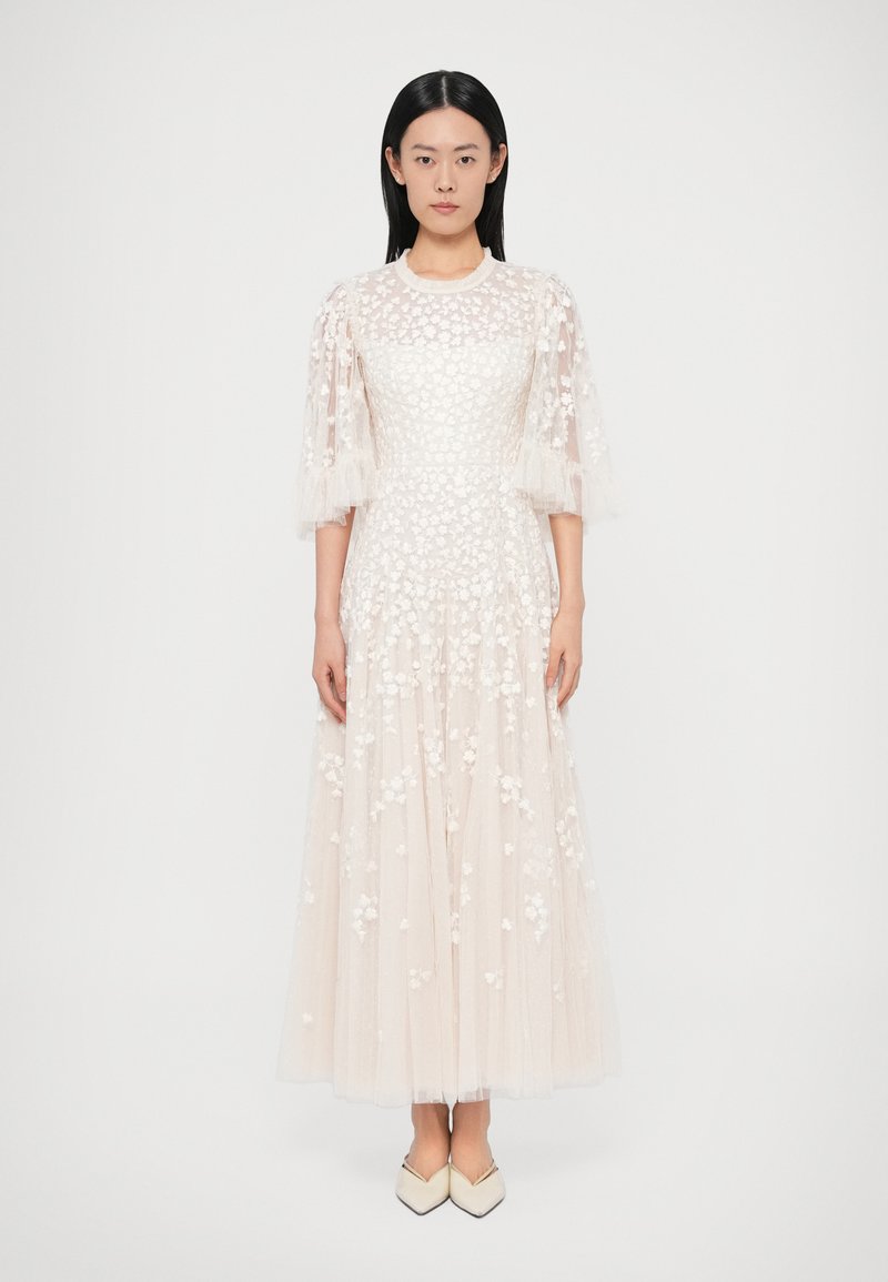 Maxi šaty z jemnej smotanovej látky so sieťovanými nadýchanými rukávmi, kvetinovou výšivkou a viacvrstvovou tylovou sukňou, doplnené špicatými topánkami.