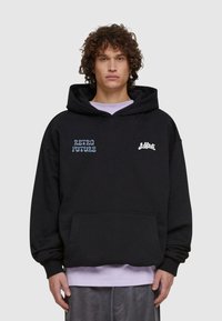 Felpa nera in cotone, con tasca a marsupio. Testo 'RETRO FUTURE' in azzurro chiaro a sinistra e un logo bianco a destra.