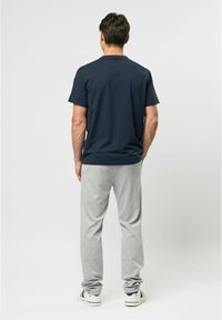 Navy cotton t-shirt with a round neck, paired with light grey sweatpants. The pants feature an elastic waist and a relaxed fit, with white sneakers.
