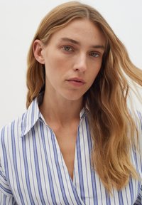 Camicia a righe blu e bianche con colletto, caratterizzata da un design a V e un tessuto textures. Finitura liscia con stile casual.