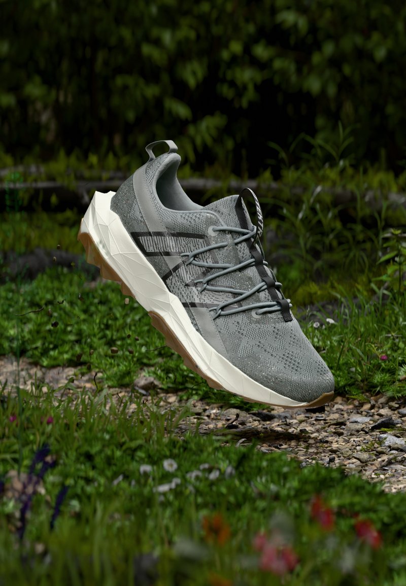 Männersportschuh, graues Textil-Obermaterial mit strukturiertem Muster, flexible Schnürung, weiße und cremefarbene Sohle mit dreieckigen Formen, Gummitraktionssohle.