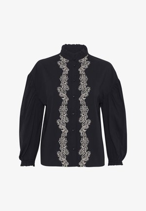 Blouse noire avec un col haut, ornée de délicates broderies florales blanches sur le devant, et de manches bouffantes avec des poignets élastiques.
