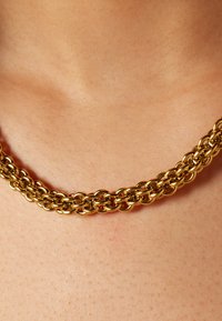 Gouden ketting met in elkaar grijpende schakels, met een gladde, glanzende afwerking en een ontwerp met meerdere strengen. Geen zichtbare sluiting.