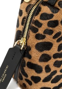 Borsa in pelliccia a stampa leopardata con zip dorata e etichetta in pelle nera impresso con "Vannichiarini Firenze" in lettering dorato.
